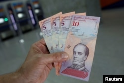 A man shows the new five and ten Bolivar Soberano (Sovereign Bolivar) bills, after he withdrew them from an automated teller machine (ATM) at a Mercantil bank branch in Caracas, Venezuela, Aug. 20, 2018.