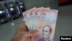 一名男子在委内瑞拉加拉加斯的银行取款后，展示新的钞票。（2018年8月20日）。