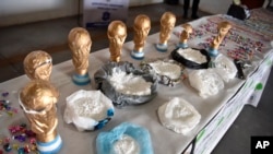 This June 21, 2018, photo, released by the National Security Ministry, shows fake World Cup trophies stuffed with cocaine, and the product itself on display next to the trophies, in Buenos Aires, Argentina.