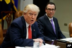 Treasury Secretary Steven Mnuchin listens as President Donald Trump speaks during a meeting on the federal budget, Feb. 22, 2017, in the Roosevelt Room of the White House in Washington.