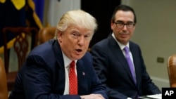 FILE - Treasury Secretary Steven Mnuchin listens at right as President Donald Trump speaks during a meeting on the Federal budget, Feb. 22, 2017, in the Roosevelt Room of the White House in Washington.