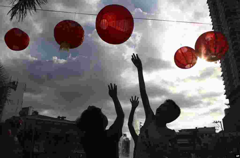Filipino boys play with red lanterns that are displayed at a park in Manila, Philippines.