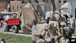 Soldiers and residents stand over covered debris, as it was moved out by military vehicles from the compound within which al-Qaida leader Osama bin Laden was killed, in Abbotabad, May 2, 2011