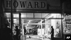 FILE- In this April 4, 1968 file photo, glass and mannequins litter a sidewalk of a clothing store in Northwest Washington after crowds broke into and took items from some stores following the news of Dr. Martin Luther King Jr.'s assassination. (AP Photo/Charles Harrity)