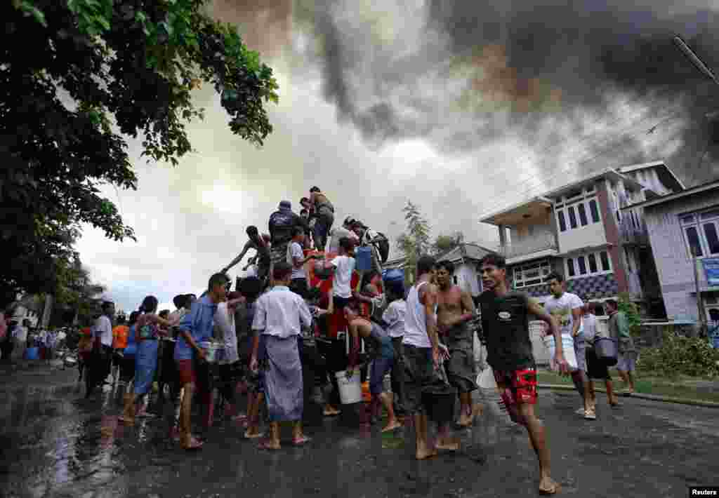 Người sắc tộc Rakhine lấy nước từ xe chữa cháy để tìm cách dập tắt đám cháy lan ra nhà cửa của họ ở Sittwe, ngày 10/6/2012