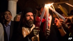 A Greek Orthodox priest lights the candles of faithful with Holy Fire brought from Jerusalem outside a church in Athens, April 30, 2016. 