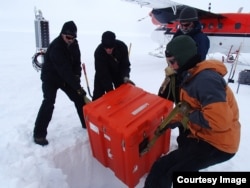 A seismic station in the process of being installed. The large orange box contains about 200 kilograms worth of batteries, electronics to that help operate the station, which will be lowered into a hole. (Credit: Lindsey Kenyon)