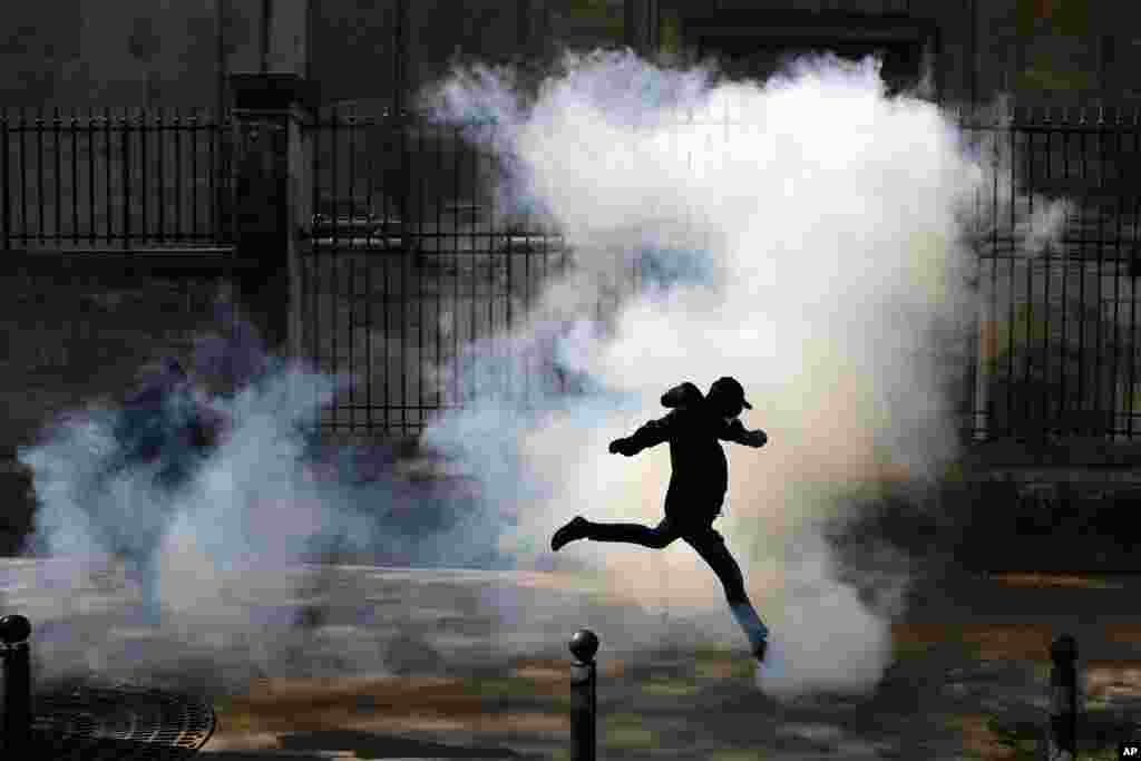 An activist kicks a tear canister gas shot by riot police during a protest in support of the French railway employees, in Paris, France.