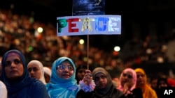 Seorang perempuan memegang plakat bertuliskan 'Perdamaian' dalam sebuah konferensi perdamaian Islamis di Wembley Arena, London. (Foto: Dok)