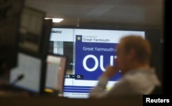 A traders works as EU Referendum results come in on a giant screen behind, in London, Britain, June 24, 2016.