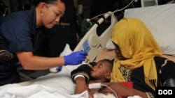 Hospital Corpsman 2nd Class Katherine Stafford treats a mother and child after a medical evacuation aboard the multipurpose amphibious assault ship USS Bataan in the Mediterranean sea, June 7, 2014. (U.S. Navy photo by Mass Communication Specialist Seaman Aaron T. Kiser) 