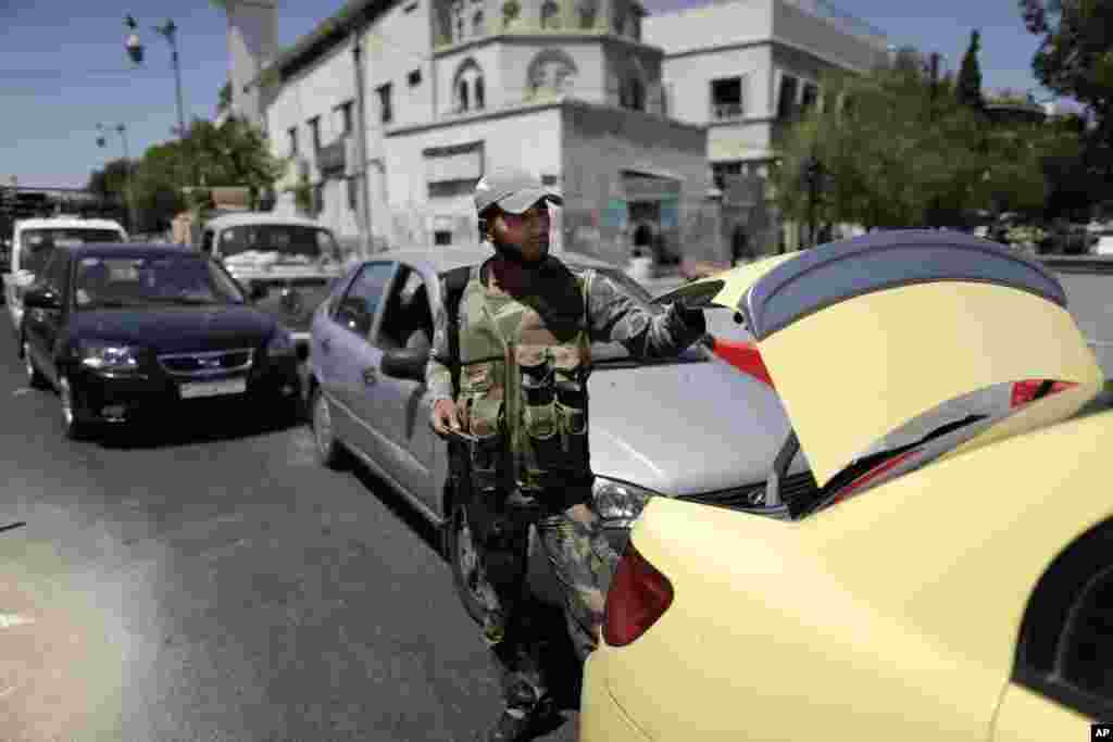 A Syrian military soldier checks the trunk of a car at a check point on Baghdad street, in Damascus, August 21, 2013.