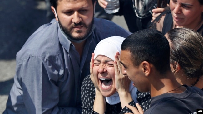 The wife of Rami Kaaki, one of ten firefighters who were killed during the last week's explosion that hit the seaport of Beirut, mourns during her husband's funeral at the firefighter headquarters, in Beirut, Lebanon, Tuesday, Aug. 11, 2020.