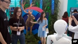 2018年7月4日在北京举行的2018百度AI开发者大会期间，一名女子在鹿的复制品旁边摆拍，尝试机器视觉识别仪器。该活动旨在将开发商，企业和个人同百度的人工智能资源联系起来。