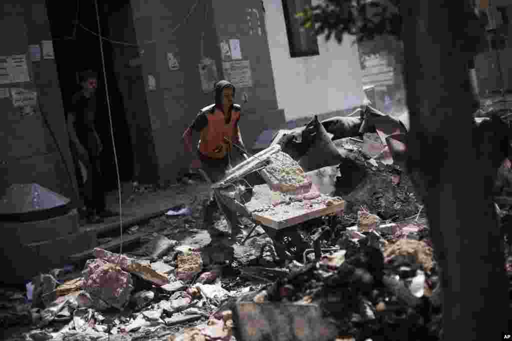 An Egyptian man pushes a wheelbarrow with debris from inside the Rabaah Al-Adawiya mosque in Nasr city, Cairo, August 21, 2013.