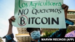 Un homme tient une banderole sur laquelle est écrit "Les agriculteurs ne veulent pas de bitcoin" lors d'une manifestation contre la circulation du bitcoin à San Salvador, le 7 septembre 2021.