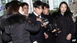 Seungri, center, member of a popular K-pop boy band Big Bang, arrives at the Seoul Metropolitan Police Agency in Seoul, South Korea, March 14, 2019.