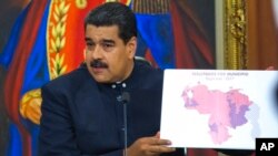 El presidente de Venezuela, Nicolás Maduro, sostiene un mapa de Venezuela con las regiones resaltadas en rojo donde los candidatos progubernamentales obtuvieron la victoria en una conferencia de prensa en Caracas. Octubre 17, 2017.