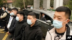 世界衛生組織的專家達扎克在湖北省武漢市進行了實地考察後，乘坐汽車離開湖北疾病預防控制中心的一排安全人員。（2021年2月1日）