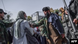 Anggota Taliban menghentikan protes perempuan untuk hak-hak perempuan di Kabul, 21 Oktober 2021. Taliban dengan keras menindak liputan media tentang protes hak-hak perempuan di Kabul pada 21 Oktober pagi, memukuli beberapa wartawan. (BULENT KILIC / AFP)