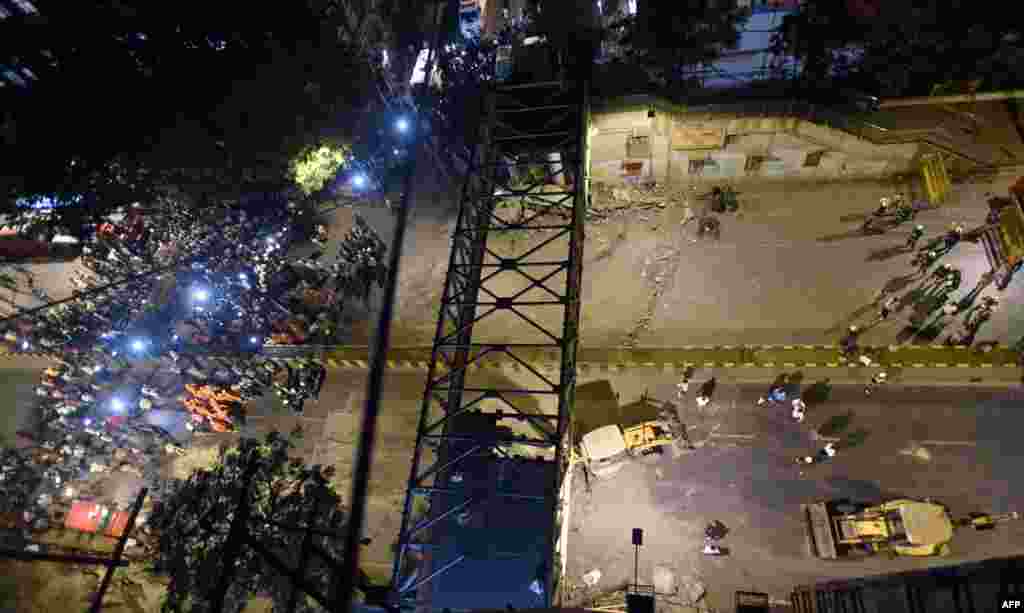 Onlookers and office-goers gather around injured people after a bridge collapsed outside the Chhatrapati Shivaji Maharaj Terminus railway complex in Mumbai, India.