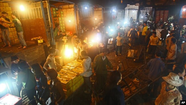 FILE - In this March 9, 2013 photo, porters unload boxes of Chinese fruits near traders at Long Bien wholesale market for fruits and vegetables in Hanoi, Vietnam.