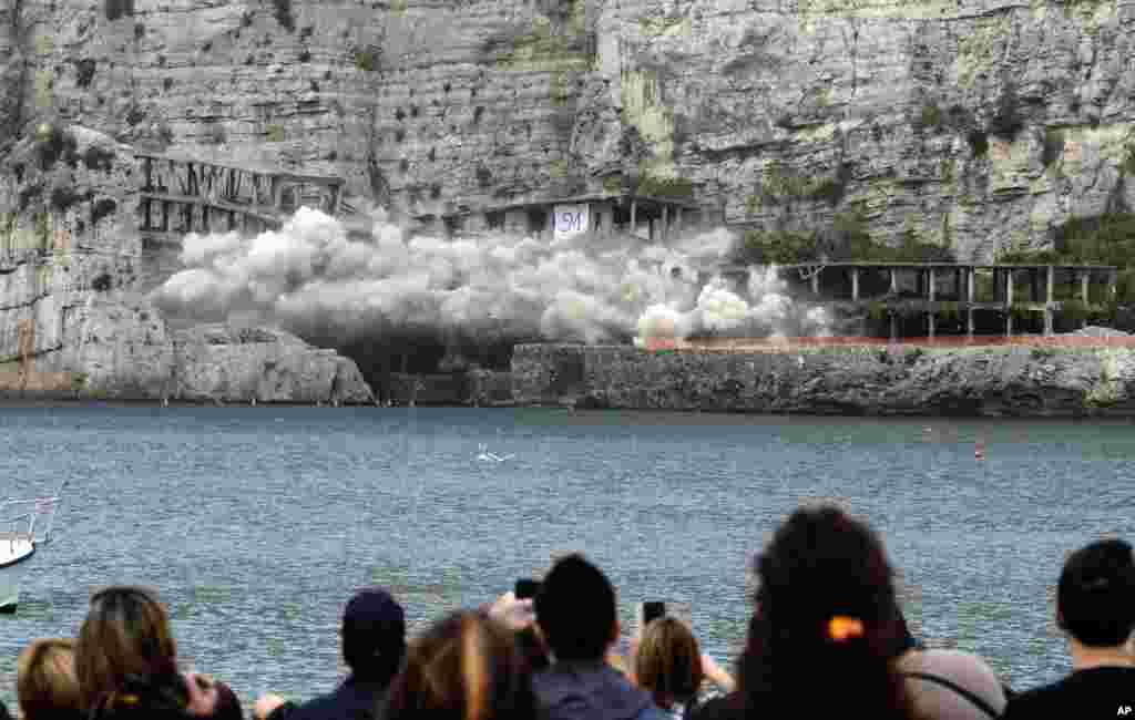 People watch as the cement structure of a 50-year-old illegally built hotel is blown up on the Sorrento coast in southern Italy.