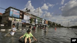 A Thai woman sits on an inflated tire as people leave flooded areas in Bangkok, Thailand, October 26, 2011.