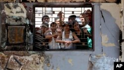 Inmates look out from inside a burnt down office at Tanjung Gusta prison following a prison riot in Medan, North Sumatra, Indonesia, July 12, 2013. 