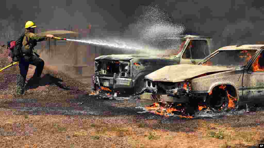 Un pompier essaye d&#39;éteindre l&#39;incendie sur des voitures en feu à Lower Lake, en Californie, le 14 août 2016.