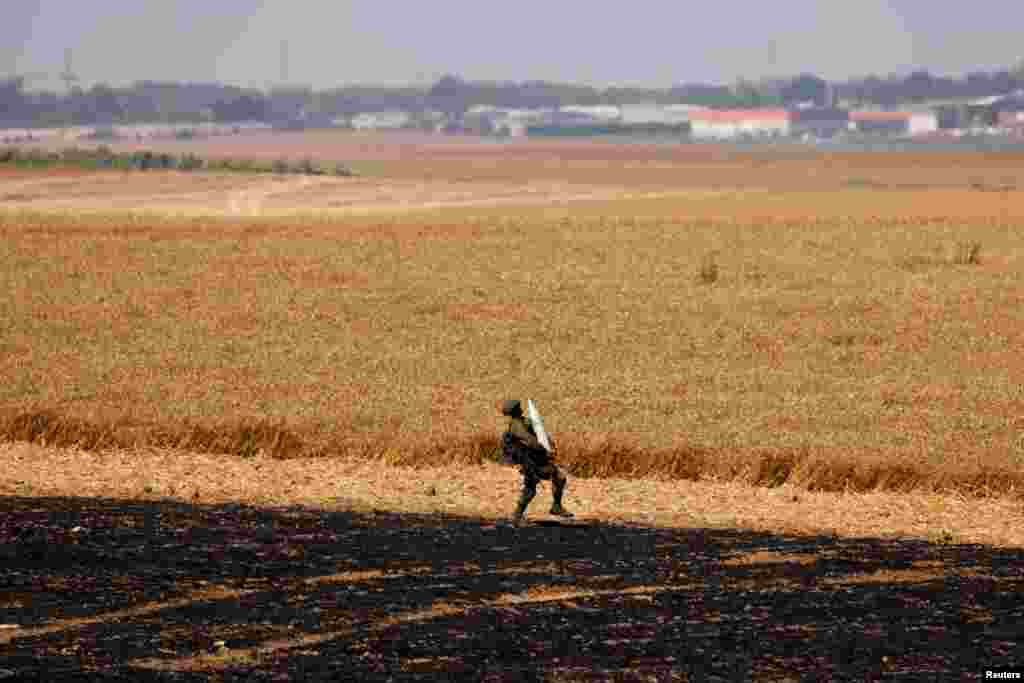 An Israeli soldier carries an artillery shell in a field next to his artillery unit near the border between Israel and the Gaza Strip, on its Israeli side.
