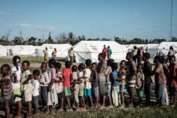 Anak-anak mengantri untuk menerima distribusi makanan dari supermarket lokal di pusat evakuasi di Dondo, sekitar 35 km sebelah utara dari Beira, Mozambik, pada 27 Maret 2019. (Foto: Yasuyoshi CHIBA/AFP)