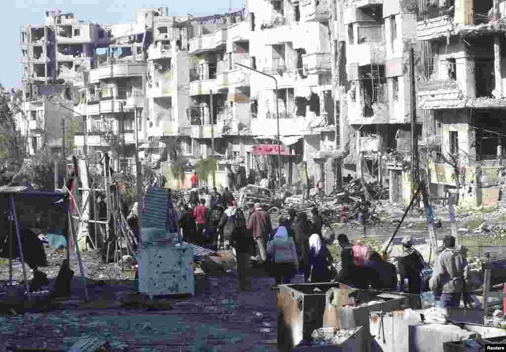 Civilians carry their belongings as they walk towards a meeting point to be evacuated from a besieged area of Homs, Feb. 9, 2014. 