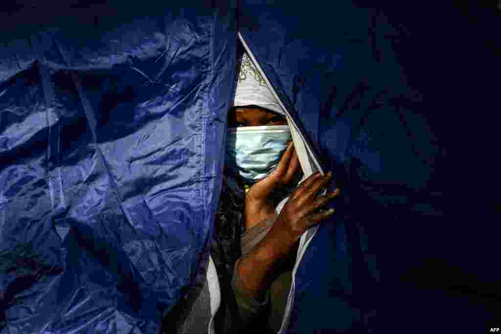 A Somalian woman peers out of her tent at a makeshift camp set up overnight by volunteers of the Utopia 56 charity and housing over 50 migrants, including refugees and asylum-seekers, along the Bassin de la Villette in Paris.