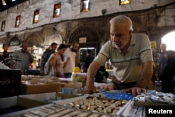 A man inspects sweets ahead of Eid celebrations in al-Bazourieh Souk in Damascus, Syria, Sept. 10, 2016.