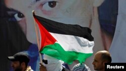 Người Palestine đứng trước 1 tấm áp phích in hình Mohammed Abu Khudair trong tang lễ của em ở Shuafat, 4/7/2014.