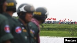 រូបឯកសារ៖ ប៉ូលិស​កម្ពុជា​ឈរ​យាម​ល្បាត​ ខណៈ​ដែល​ប្រជាជន​វៀតណាម​លើក​ទង់ជាតិ​របស់​ខ្លួន​គ្រវី​ឡើង នៅ​ឯ​ព្រំដែន​រវាង​កម្ពុជា​និង​វៀតណាម ក្នុង​ខេត្ត​ស្វាយរៀង ថ្ងៃទី១៧ ខែកញ្ញា ឆ្នាំ​២០១៥។ REUTERS/Samrang Pring