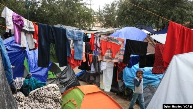 Un niño camina entre la ropa puesta a secar después de una intensa lluvia en el campamento de carpas de Reynosa, México. Foto Dylan Baddour/VOA.