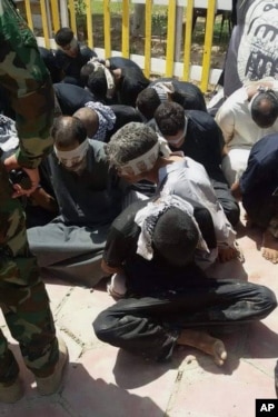 Iraqi security forces and Peace Brigades, a Shiite militia group loyal to Shiite cleric Muqtada al-Sadr, detain 12 fighters of the Islamic State group in Beiji, some 155 miles (250 kilometers) north of Baghdad, Iraq, June 7, 2015.