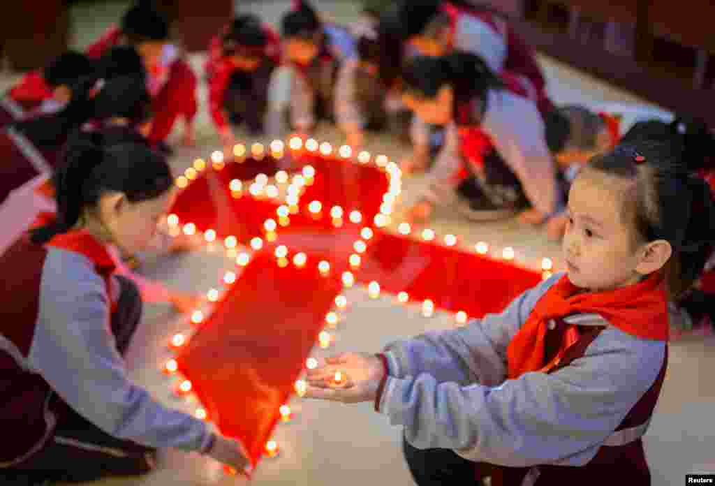 Students use candles to form a large ribbon during an event to mark World AIDS Day at a primary school in Hohhot, Inner Mongolia autonomous region, China.
