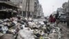 A family crosses a street piled with garbage in Aleppo, Syria, January 5, 2013.