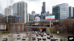 Lalu lintas di jalan raya Interstate 90 sementara kereta commuter Metra melintas di jalur layang di Chicago, 31 Maret 2021. 