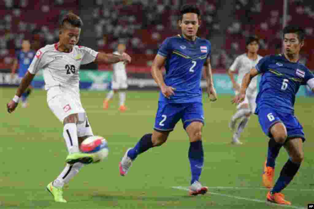 Shine Thura of Myanmar, left, attempts a shot past Peerapat Notechaiya, center, and Sarach Yooyen, right, of Thailand, during the soccer final at the SEA Games in Singapore, Monday, June 15, 2015. (AP Photo/Joseph Nair)