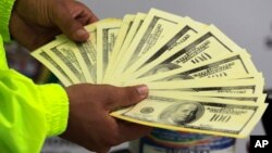 A police officer shows seized counterfeit dollars to the press in Cali, Colombia, Oct. 9, 2012. 