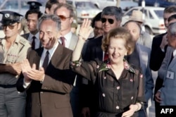 FILE - British Prime Minister Margaret Thatcher salutes as Israeli Prime Minister Shimon Peres applauds on May 25, 1986 in Jerusalem, during her four-day visit to Israel.