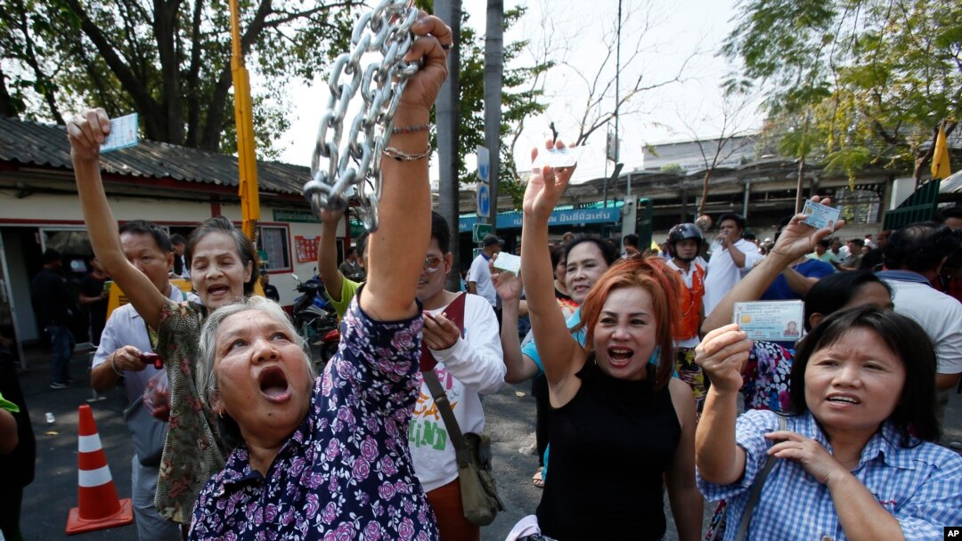 Voters hold their identification cards and the chains that held the gate of the polling station closed, as they demand the right to vote during general elections in Bangkok, Thailand, Feb. 2, 2014.