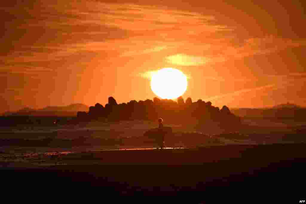 A surfer walks on the beach at sunset at Nakatajima-Sakyu Dunes in Hamamatsu, Japan.