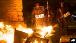 Spanish National Police officers take positions next to a burning barricade during clashes with demonstrators in Lavapies, a neighbourhood of Madrid, Spain, March 15, 2018.