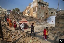 Hindu devotees walk barefoot through debris of demolished houses to reach river Ganges at the site of a proposed grand promenade, March 19, 2019. The $115 million promenade is one of a number of India Prime Minister Narendra Modi's religious glamour projects.