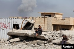 Smoke rises while displaced Iraqis wait to get food supplies as Iraqi forces battle with Islamic State militants, in western Mosul, Iraq, March 27, 2017.